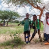 Der er varmt i det nordlige Burkina, så det er godt at få en pause under et skyggefuldt træ. Læs mærke til vandflaskerne, som de har bundet fast til hyrdestaven. Det er Ali og Hamadou, som står sammen med Teïdo. Foto: William Vest-Lillesøe